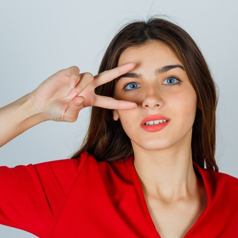 young-lady-showing-victory-sign-eye-red-blouse-looking-lucky_176474-24990